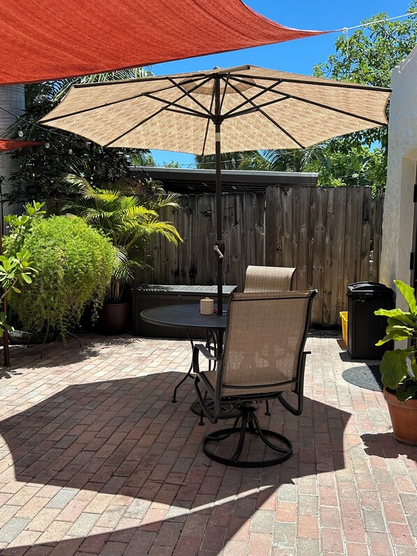 A patio with a table and chairs, a wooden fence, and potted plants. - Historic charm meets modern comfort—your cozy stay for work or play. (West Palm Beach)