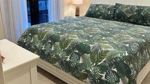 Une chambre à coucher avec un lit, une table de chevet, un ventilateur de plafond et une fenêtre avec des rideaux.