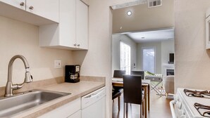 A modern kitchen with a stainless steel sink, white cabinets, a dishwasher, and a stove. - Katy Trail Cosy and Elegant (Dallas)