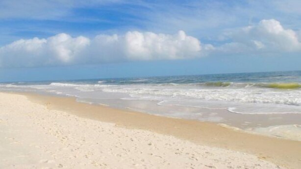 Ein Strand mit sandigem Ufer und Wellen.