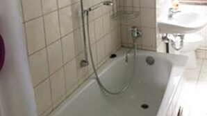 A bathroom with a bathtub, a shower, a sink, and a towel rack.