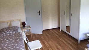 A bedroom with a bed, a wardrobe, a small table, and a chair.