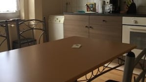 A kitchen with a wooden table, chairs, a washing machine, and cabinets.