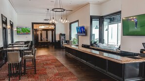 Een hotellobby met een bar, zitplaatsen en een televisietoestel waarop een sportwedstrijd wordt vertoond.