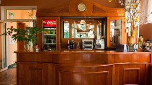 Un comptoir d’accueil en bois, avec une horloge, un réfrigérateur Coca-Cola et une plante.