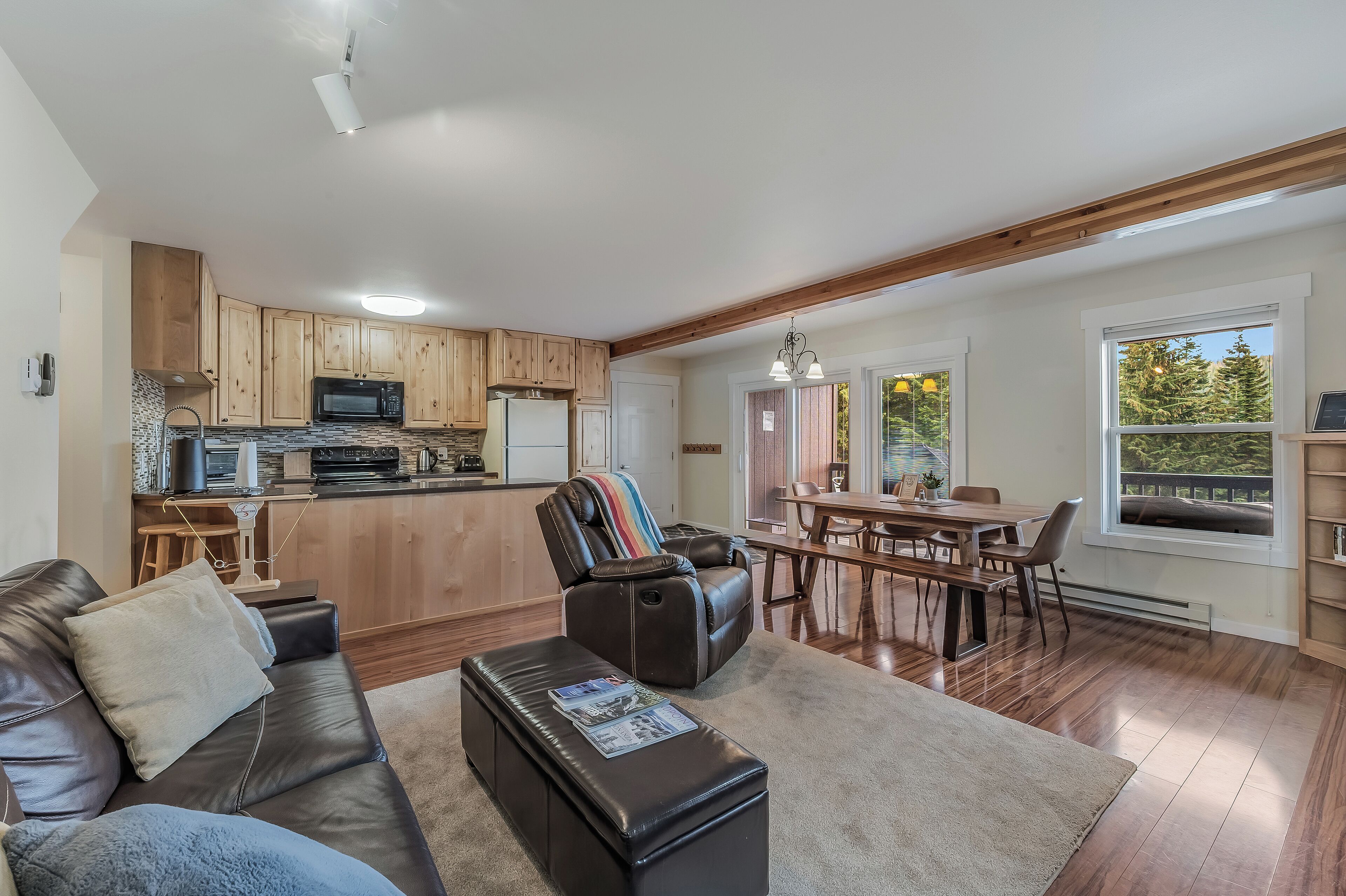 A modern kitchen with wooden cabinets, a microwave, and a dining area with a table and chairs.