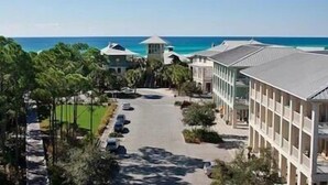 A resort with a central road, multiple buildings, and a view of the ocean.