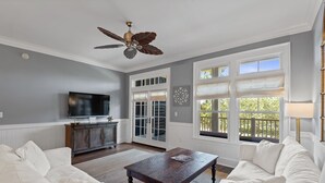A living room with a ceiling fan, a television, a wooden coffee table, and a white sofa.