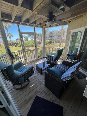 A covered outdoor seating area with wicker furniture, a ceiling fan, and a view of a residential area. - Beautiful Wild Dunes ! Enjoy the Natural Coastal Beauty! (Isle of Palms)