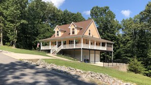 A two-story house with a covered porch, a garage, and a stone retaining wall. - Center Hill Lake, family/pet friendly custom home on 3-acre lot, 8-10 pers. (Smithville)