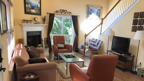 A living room with a fireplace, a television, and a staircase. - Center Hill Lake, family/pet friendly custom home on 3-acre lot, 8-10 pers. (Smithville)