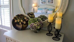 A bedroom with a bed, a bedside table with candles, a vase with flowers, and a mirror. - Beautiful, Charming, Historic Riverfront and Wrightsville Beach! (Wilmington)