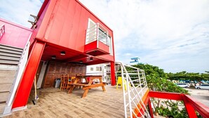 Un edificio rojo con terraza de madera y zona de estar al aire libre.