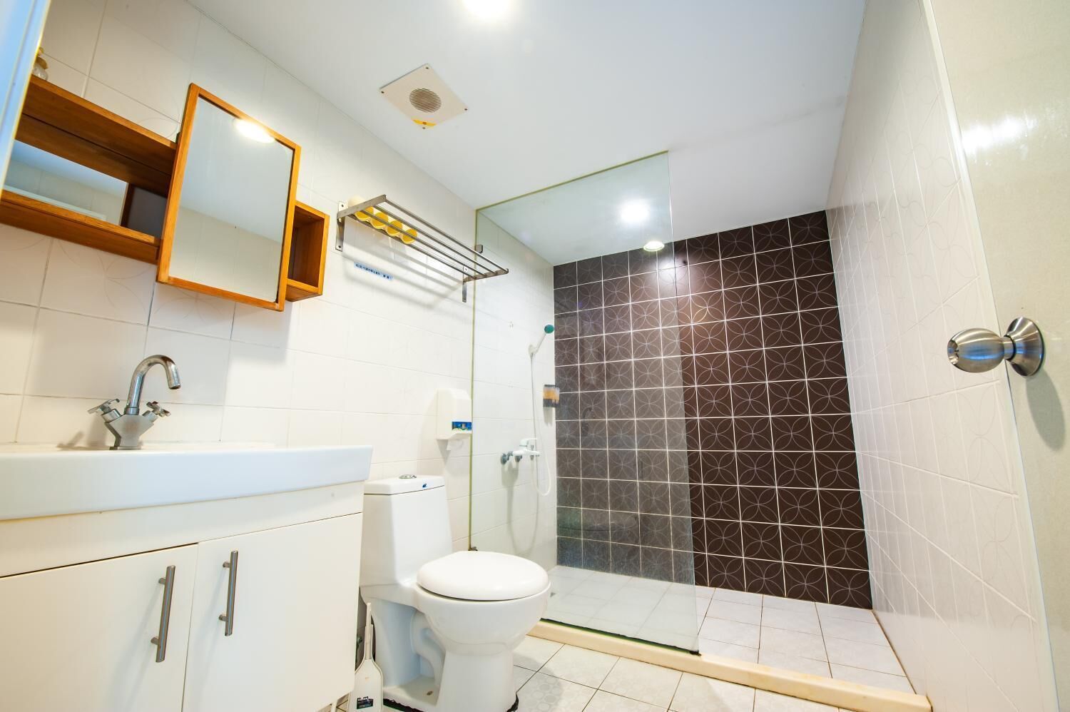 A modern bathroom with a white sink, mirror, and toilet.