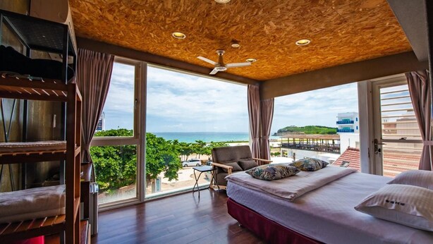 Un dormitorio con una cama grande, ventilador de techo y vistas a la playa y al océano.