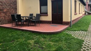 Un edificio con fachada de ladrillo, una puerta principal y un pequeño patio con una mesa y sillas.