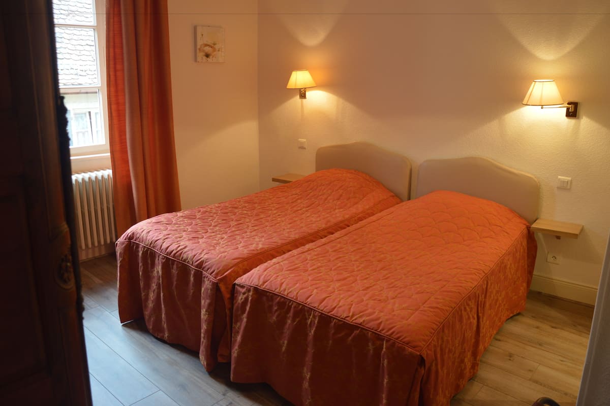 Een kamer met twee bedden, elk met een bijpassend hoofdbord en voetenbord, en twee bedlampjes.