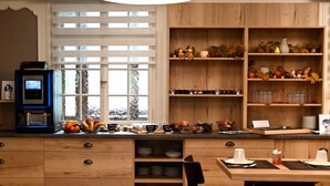 Une cuisine avec des meubles de rangement en bois, une machine à café et divers ustensiles de cuisine disposés sur le plan de travail.