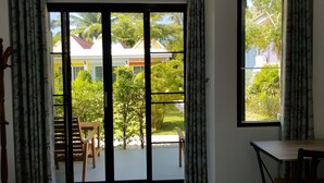 A room with a sliding glass door leading to a balcony, a wooden table, and a red rug on the floor. - Mook Ing Lay (Ko Mook)