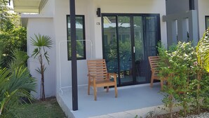 A modern house with a covered porch, two wooden chairs, and a glass door. - Mook Ing Lay (Ko Mook)