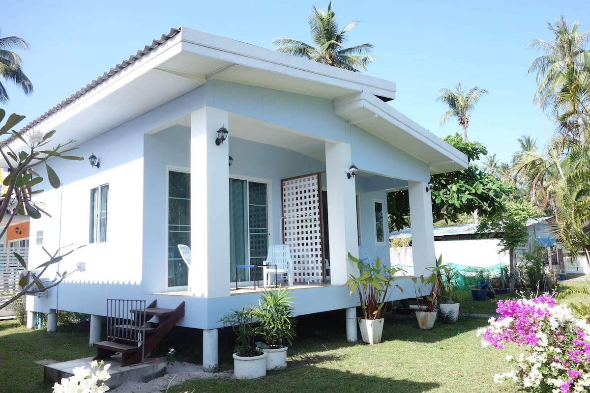 A modern house with a covered porch, large windows, and a well-maintained garden with various plants and flowers.