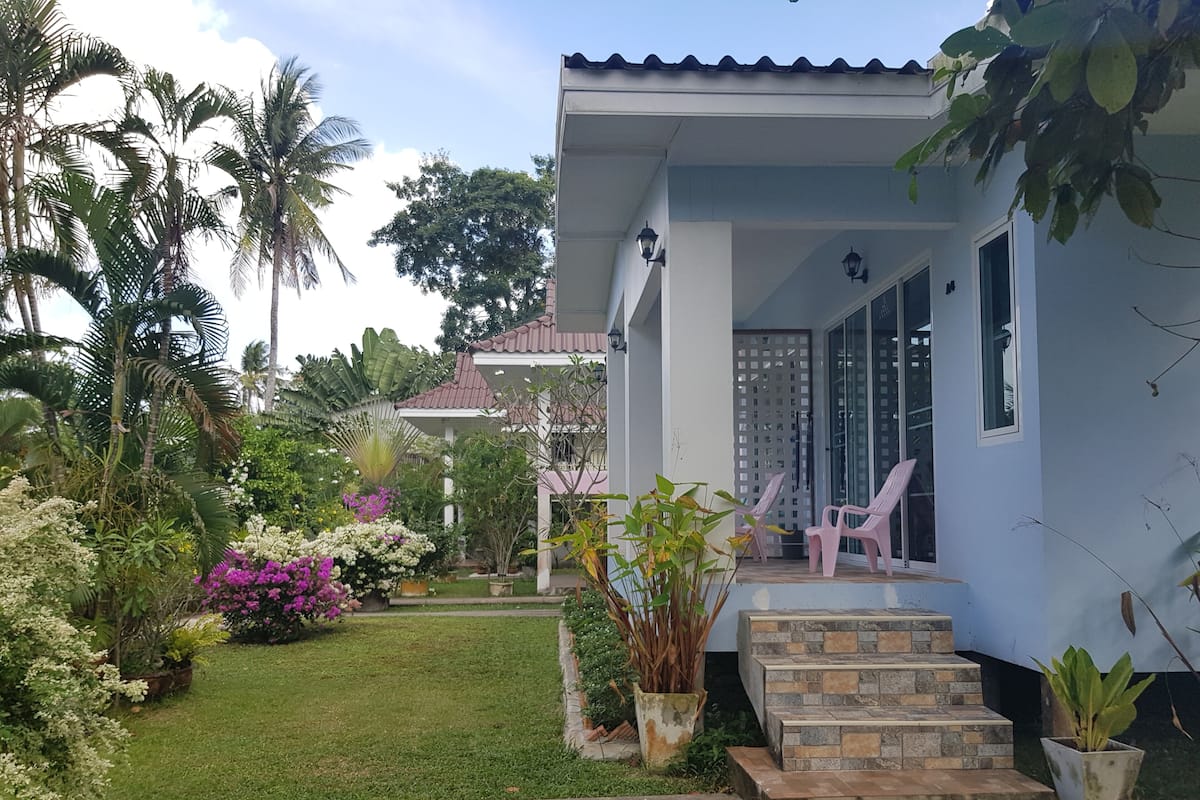 A house with a porch, steps, and potted plants.