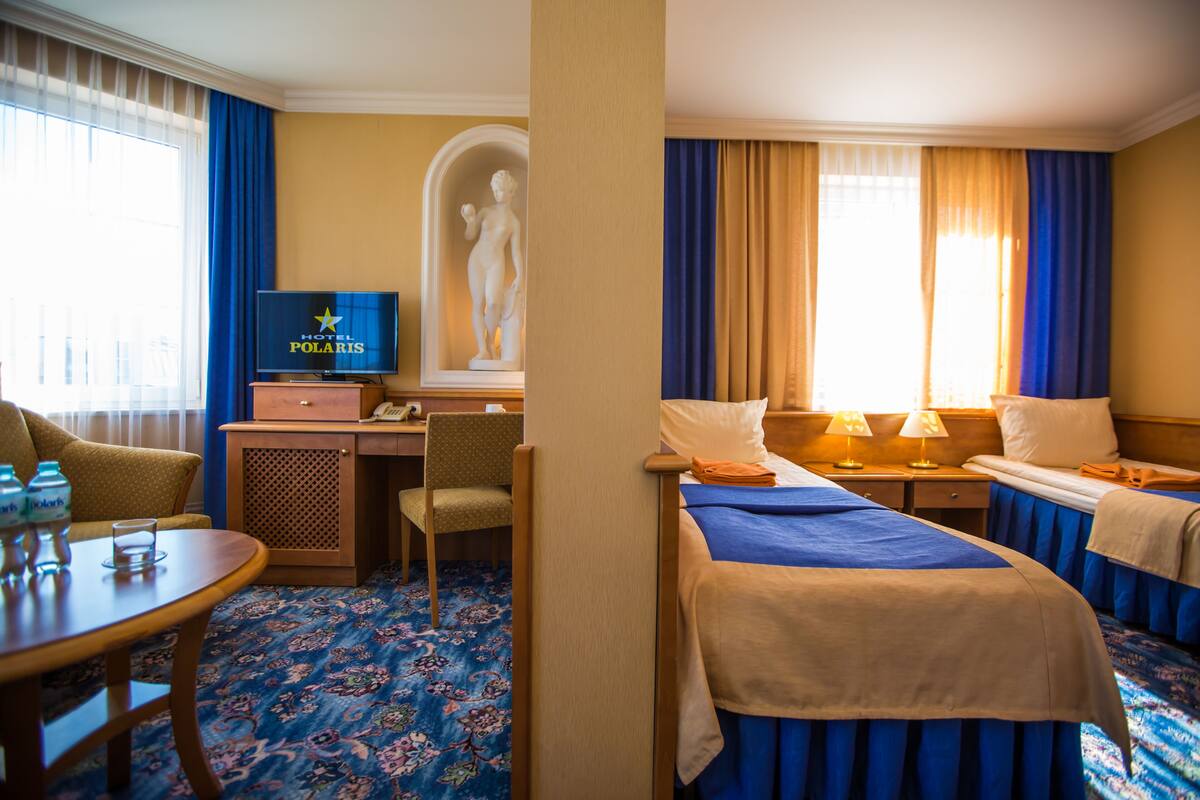 Una habitación de hotel con una cama, un escritorio, una silla, un televisor y una estatua.