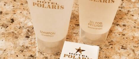 Kolme Hotel Polaris -tuotemerkin shampoota ja hoitoainetta sisältävää tuubia sekä saippuapakkaus graniittitasolla.