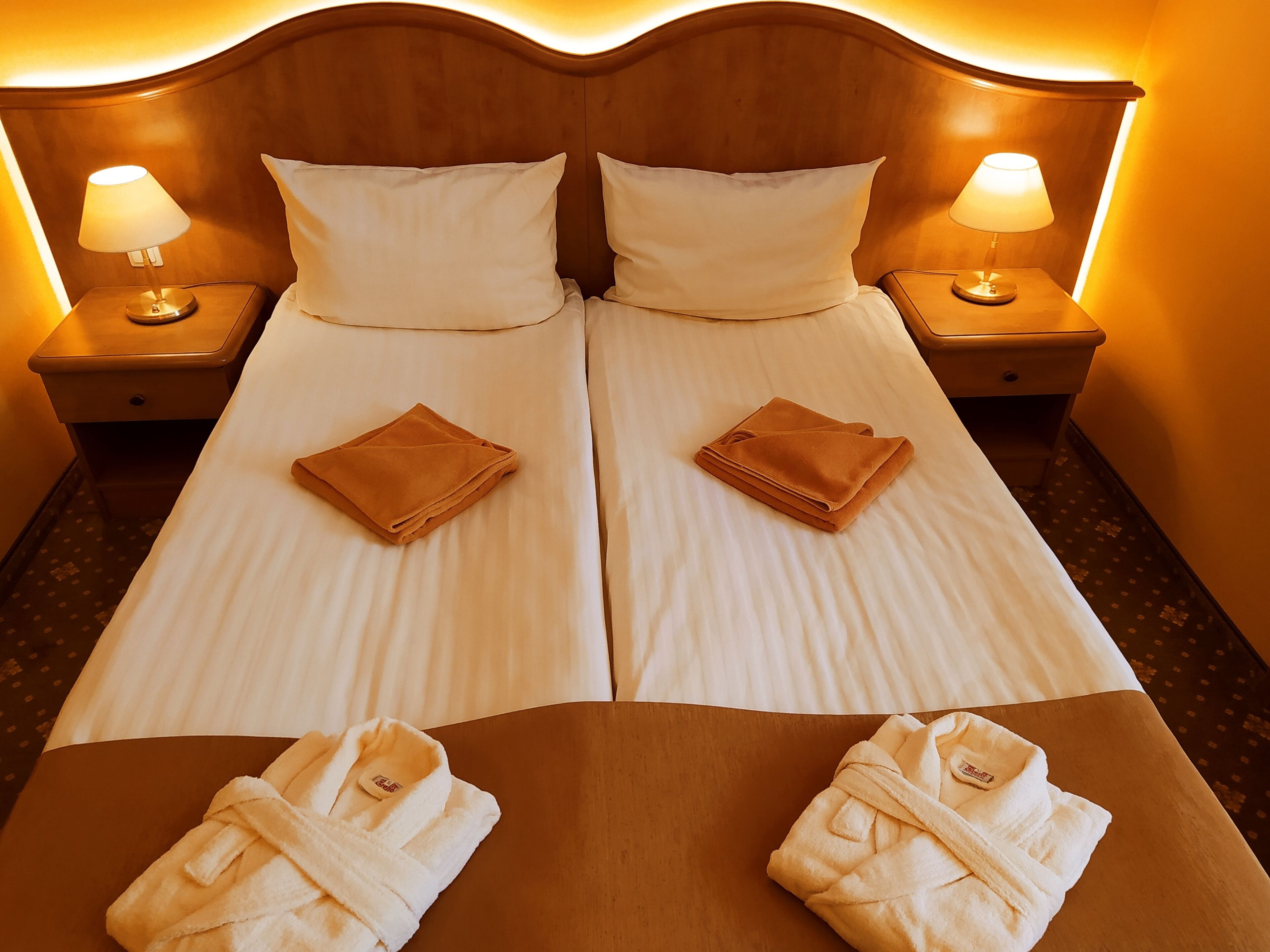 Un lit double avec deux oreillers, deux tables de chevet avec des lampes et deux serviettes sur le lit.