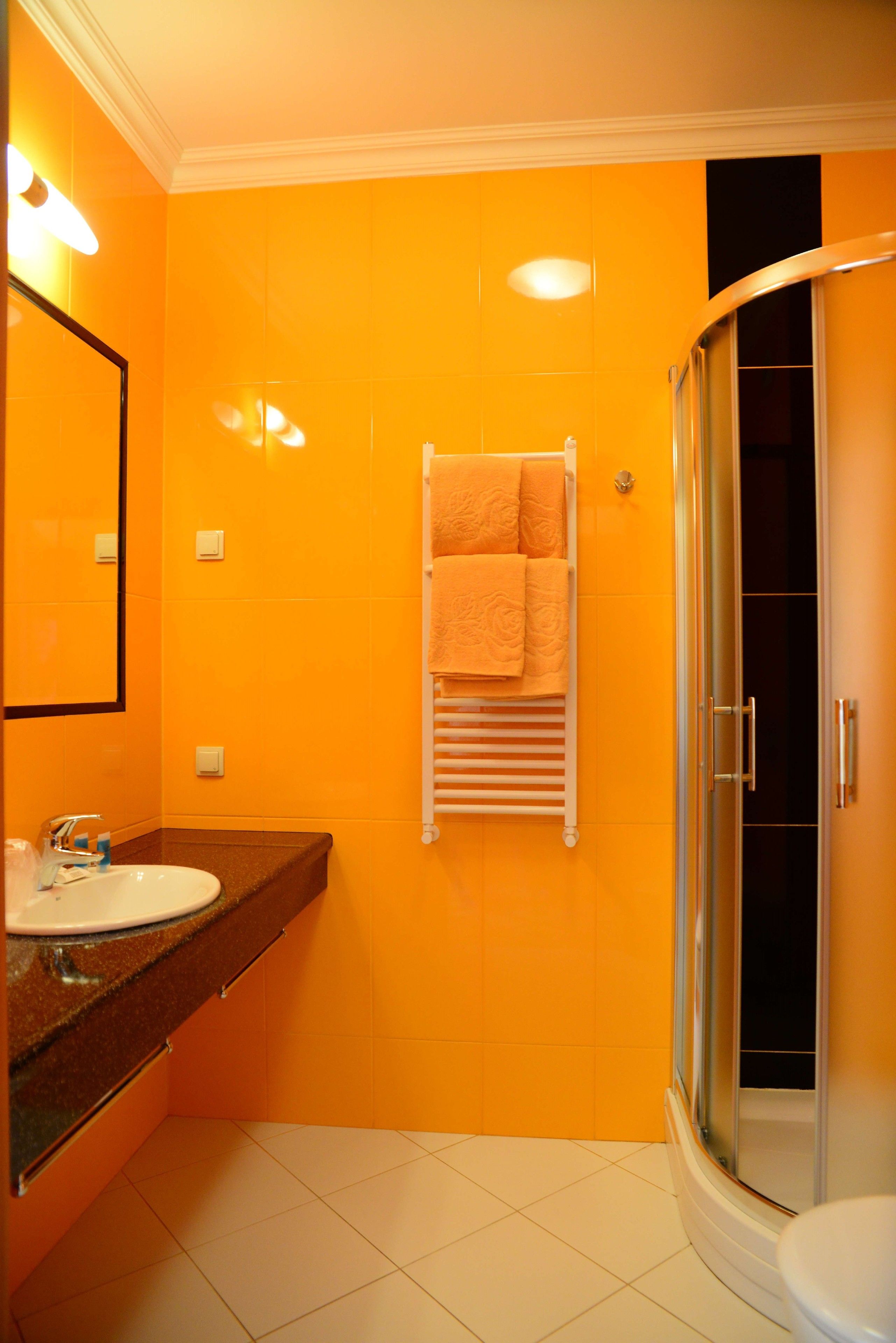 A bathroom with a white sink, a glass shower enclosure, and a towel rack with a towel.