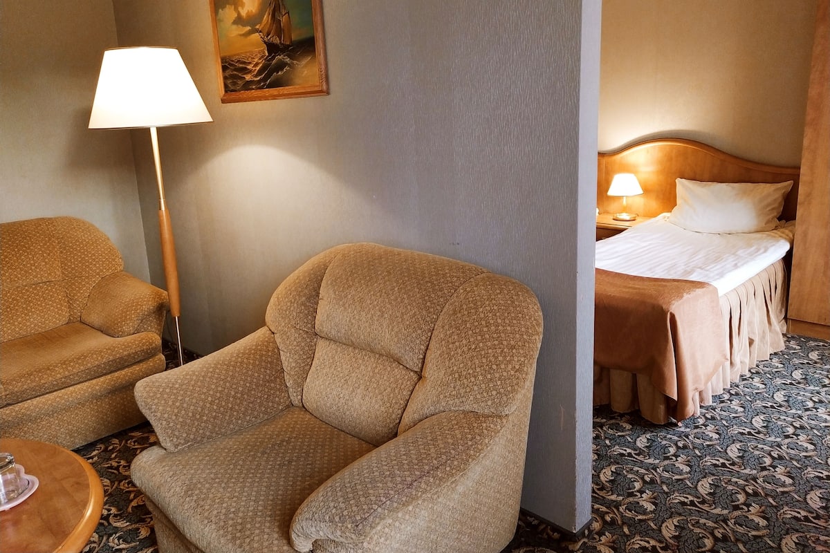 Una habitación de hotel con un sofá, una cama, una lámpara y un cuadro en la pared.