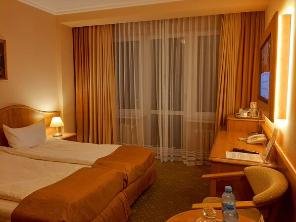 Habitación de hotel con dos camas, un escritorio con teléfono y una silla.