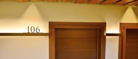 A hotel room with a wooden door, a number '106' above it, and a ceiling with wooden beams.