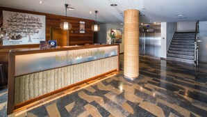 A hotel reception area with a reception desk, a staircase, and a large pillar. - Hotel Venta Baños (Murcia)