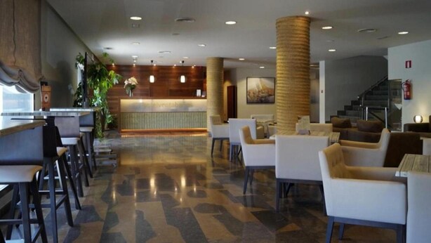 A hotel lobby with a reception desk, seating area, and staircase. - Hotel Venta Baños (Murcia)