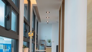 A modern hallway with wooden flooring, large windows, and built-in seating. - Galilee (Magong)