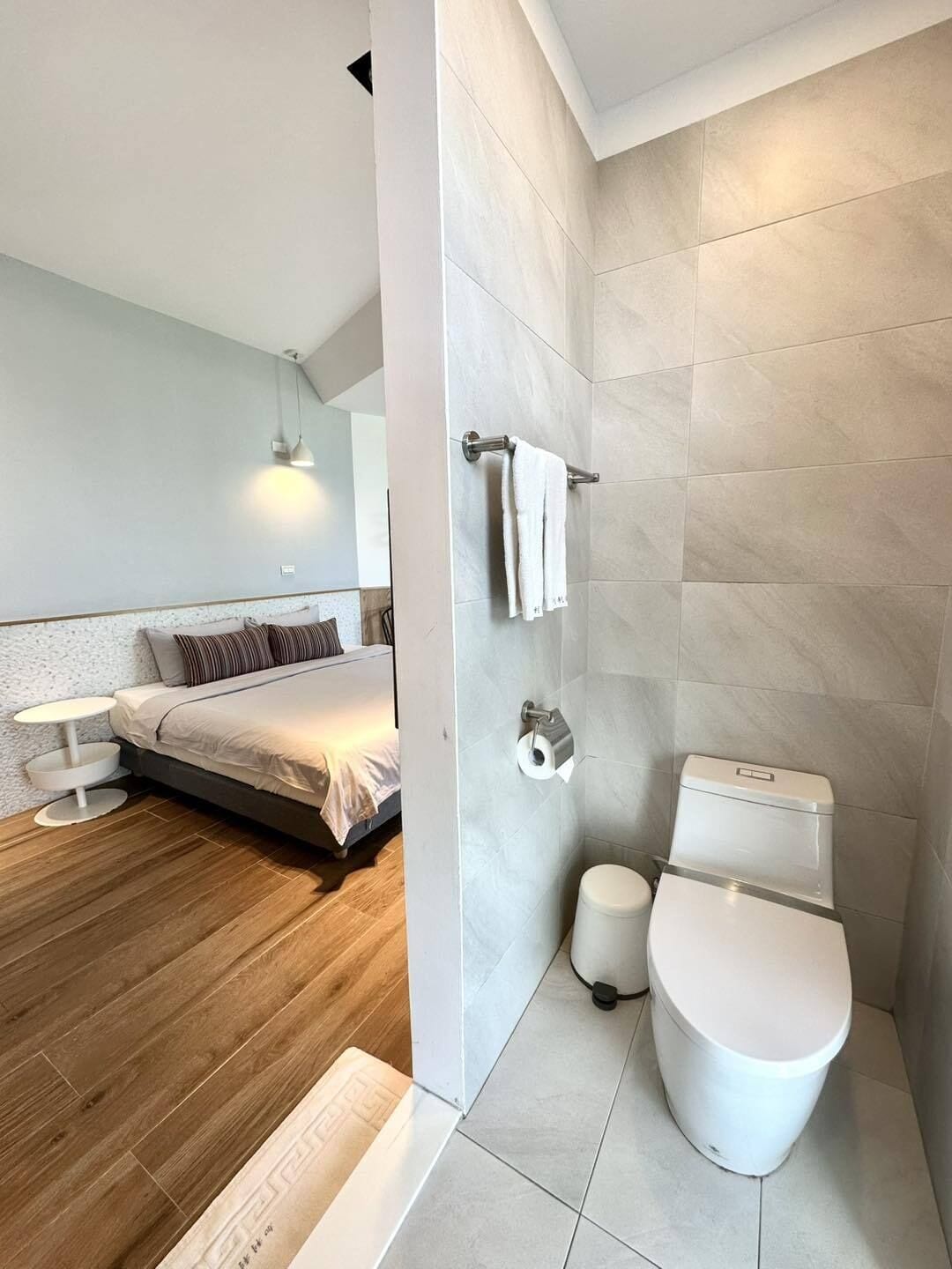 A modern bathroom with a toilet, bidet, and towel rack.