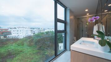 A modern bathroom with a large window, a sink, and a shower.