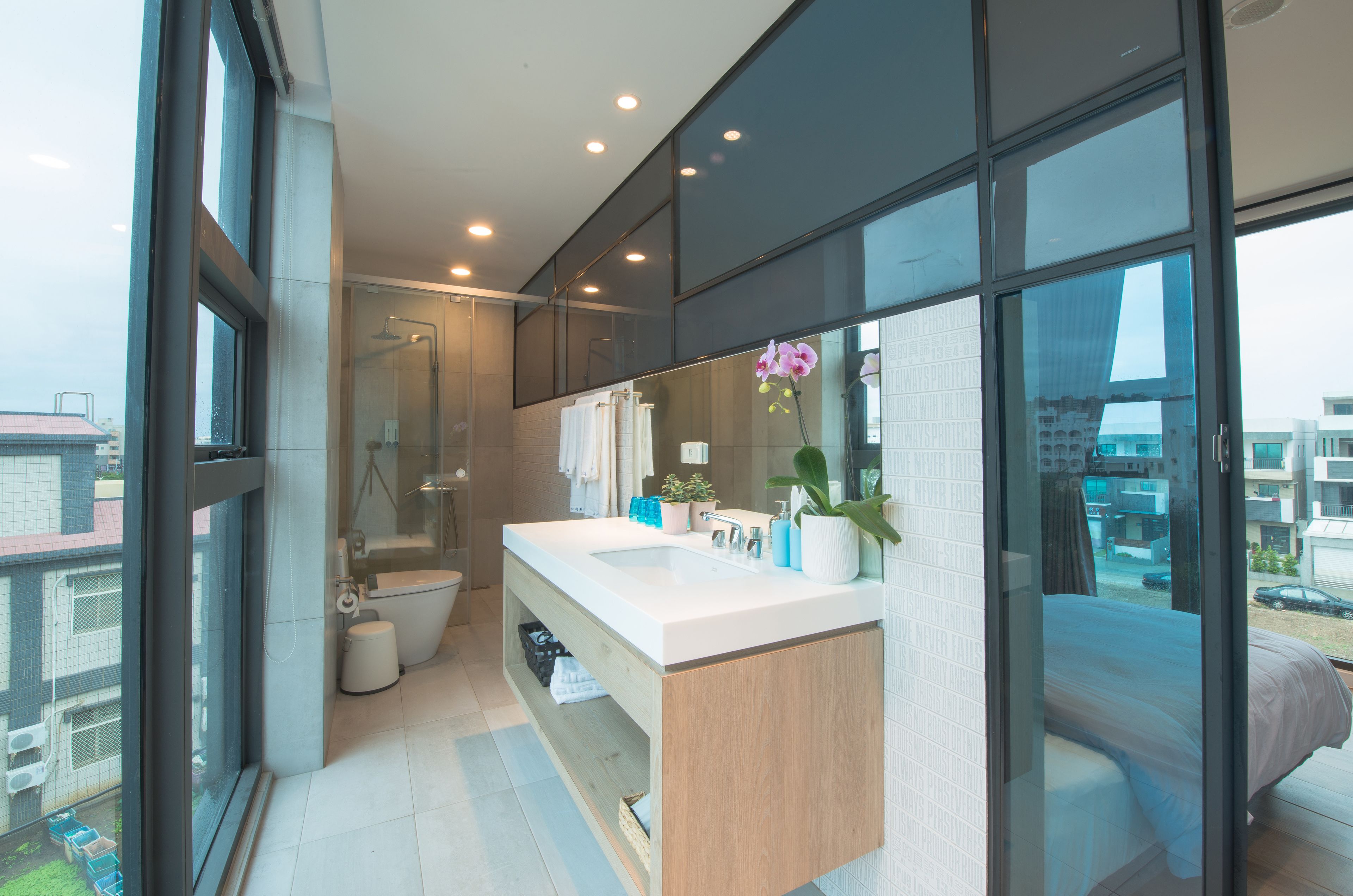 Un baño moderno con un ventanal amplio, una ducha y un lavabo con tocador.