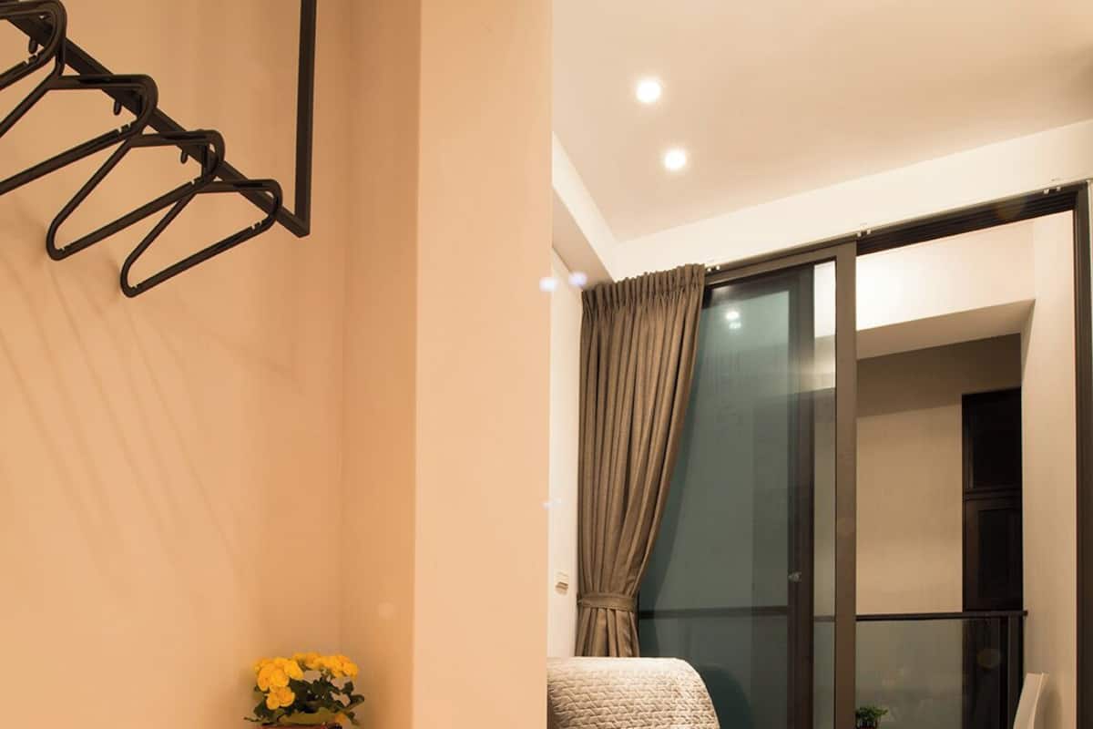 A modern living room with a sofa, a small table, a potted plant, and a wall-mounted coat rack.
