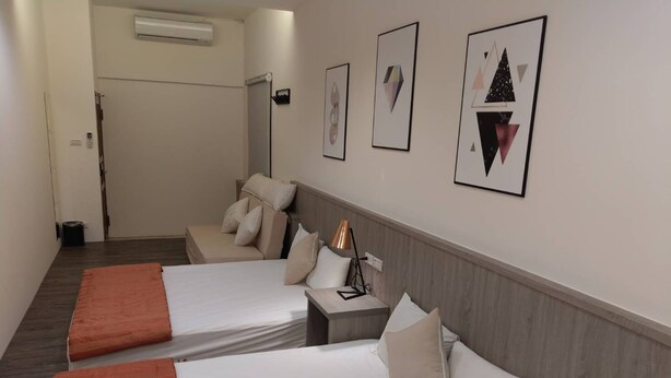 Une chambre d’hôtel avec deux lits, une table de chevet, une lampe et des œuvres d’art accrochées au mur.