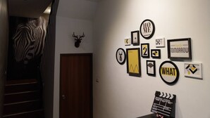 Un couloir orné d’une fresque représentant des zèbres, d’une tête de cerf et de divers tableaux encadrés accrochés au mur.
