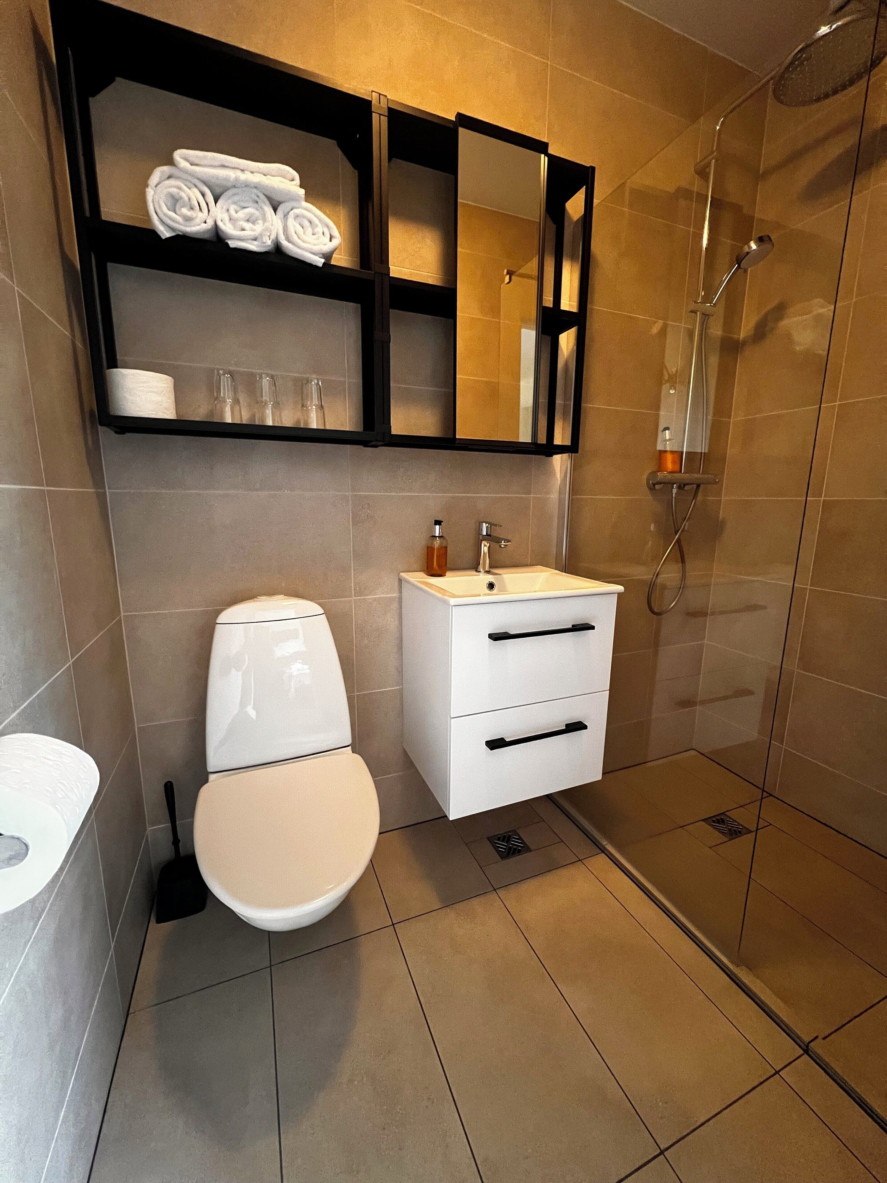 Un baño moderno con inodoro, lavamanos y ducha.