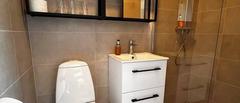 Un baño moderno con inodoro, lavamanos y ducha.