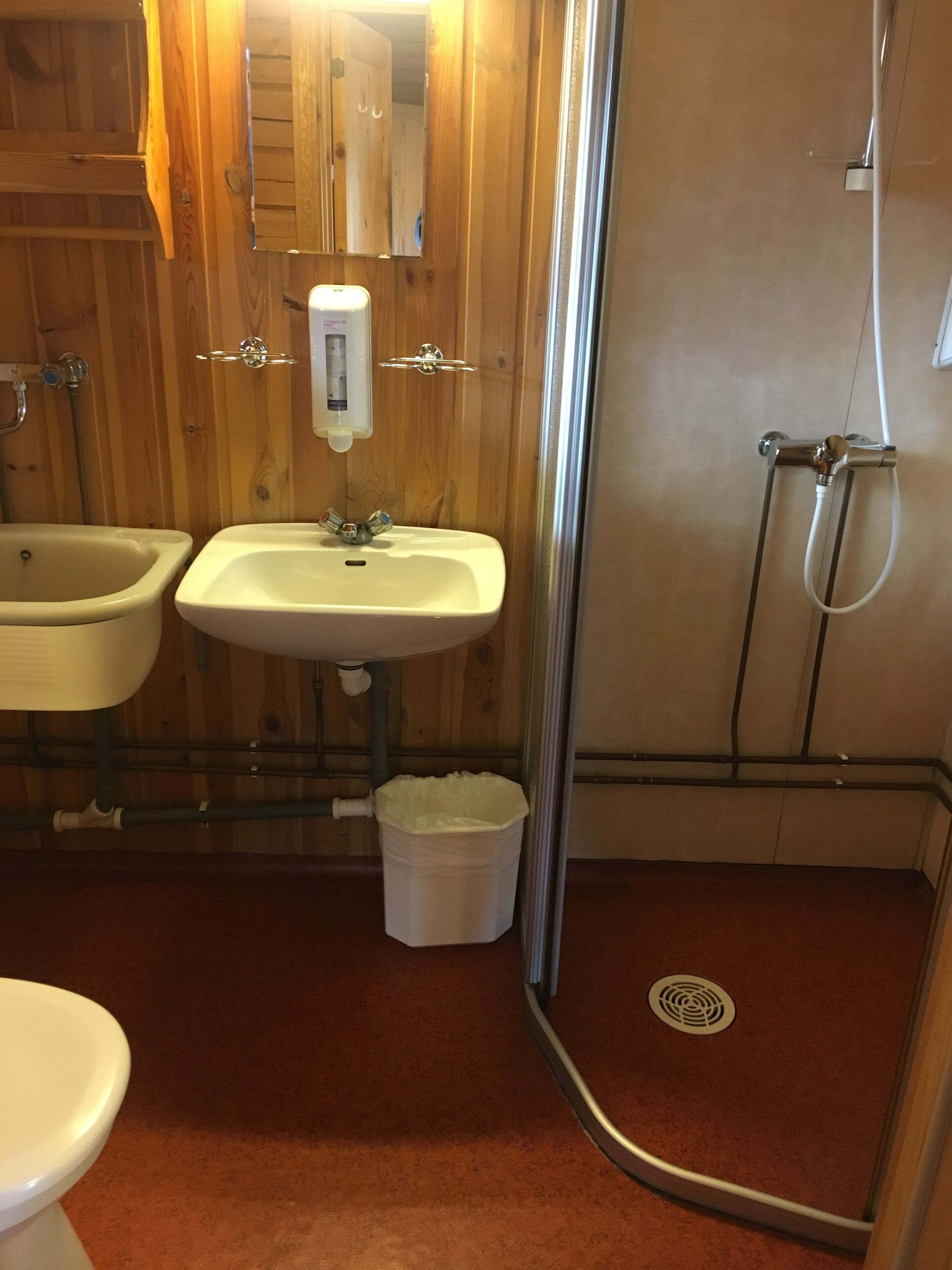 A bathroom with a wooden vanity, a sink, a toilet, and a shower area.