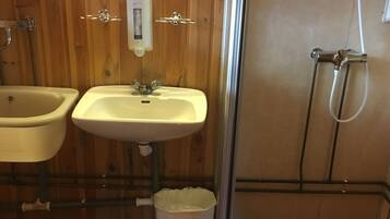 A bathroom with a wooden vanity, a sink, a toilet, and a shower area.