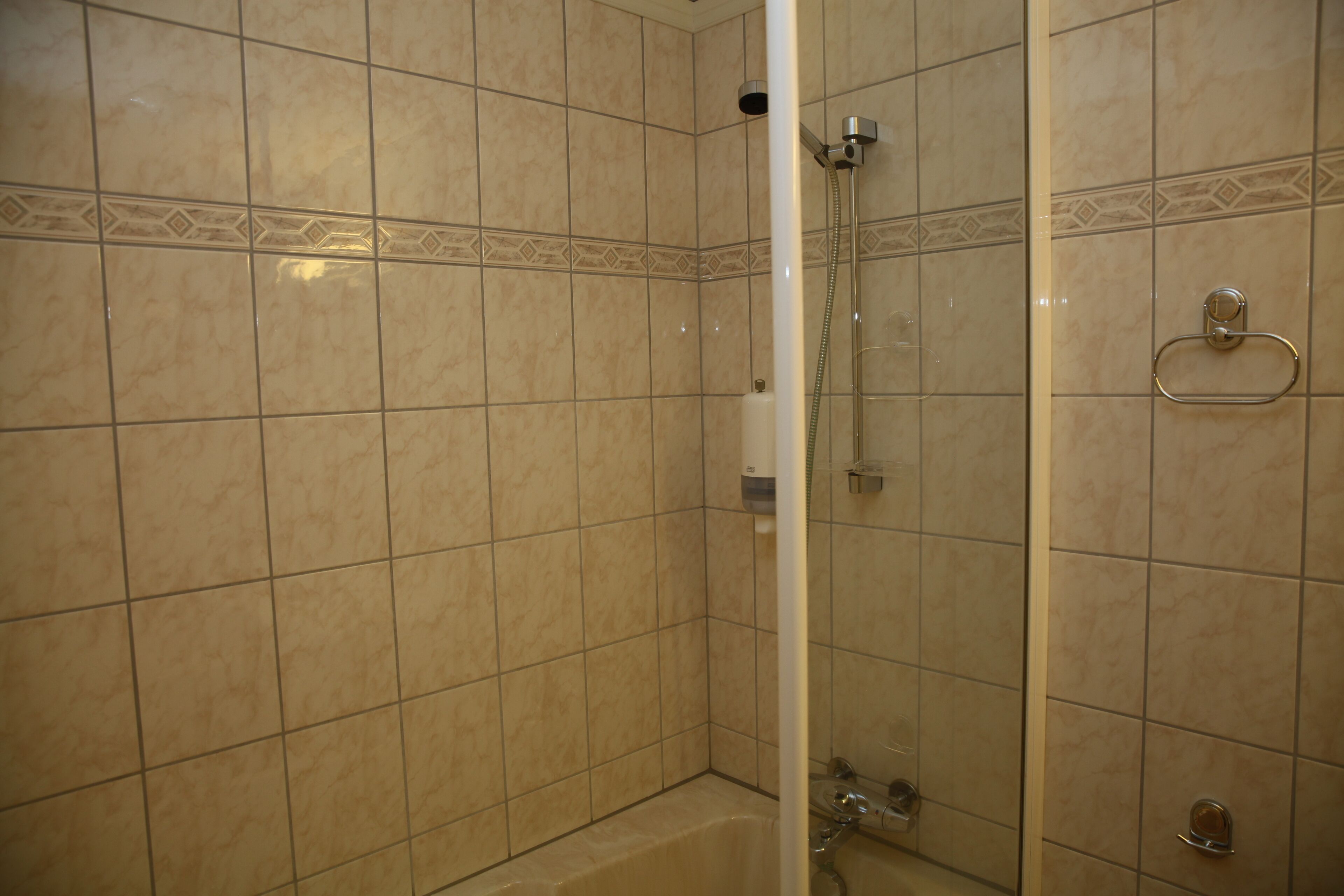 Ein Badezimmer mit beigen Fliesen, einer Dusche und einer Badewanne.