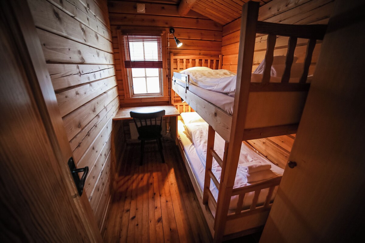 Una habitación tipo cabaña con literas, un escritorio y una silla.
