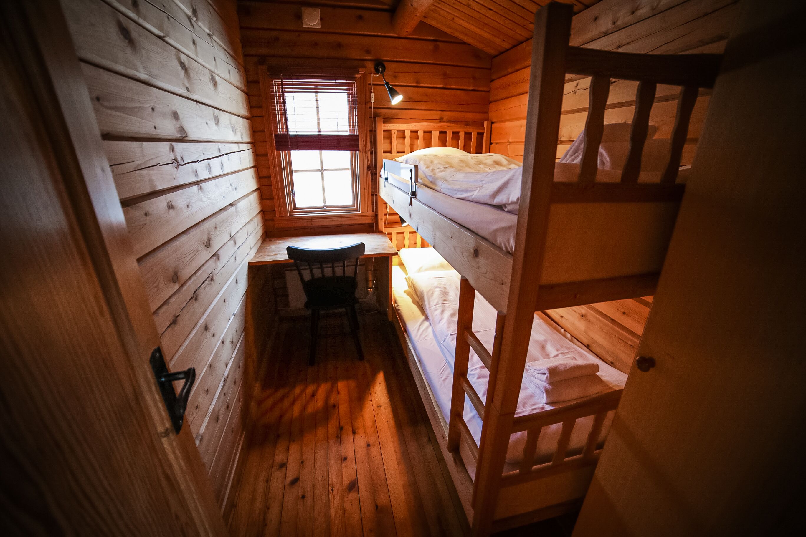 A cabin room with a bunk bed, a desk, and a chair.