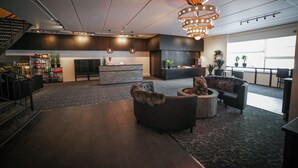 A spacious lobby with a modern design, featuring a central seating area, a staircase, and a bar area.